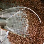 Coffee beans being roasted in an industrial steel roasting machine showing detailed processing.