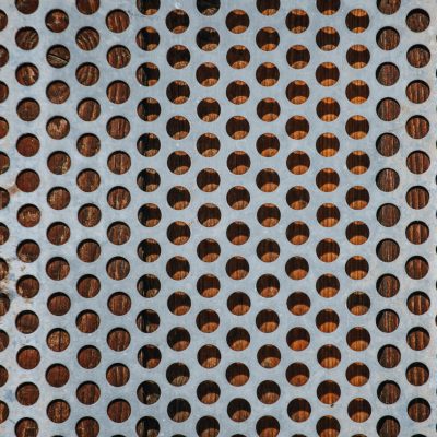 High angle view of a perforated metal sheet against a wooden surface, showcasing a unique pattern.